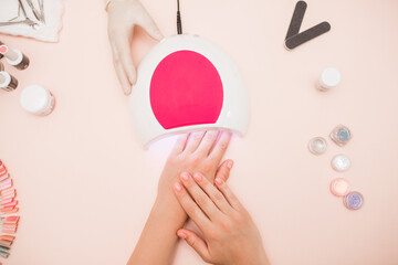 Close-up of beautiful female hands and a nail lamp on the table. Do a manicure. top view. UV lamp....