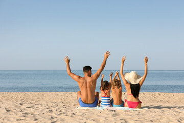 Family on sandy beach near sea, back view. Summer holidays