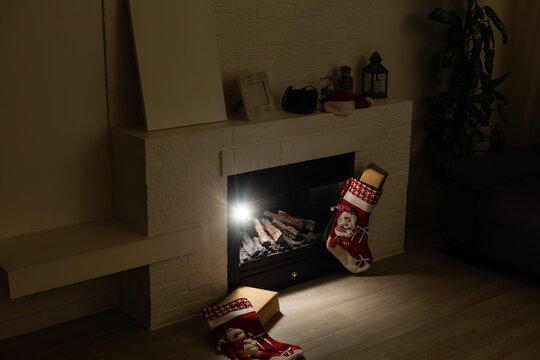 Christmas stocking hanging from a mantel or fireplace, decorated for Christmas with fire glowing.
