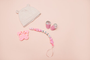 Clothes for a newborn girl: a tiny pink hat, cotton pants on a light background. baby clothes on...