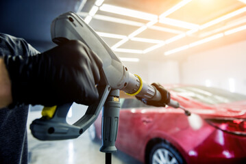 Fototapeta premium Worker washing car with high pressure water at a car wash.