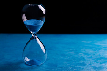 Sandglass, egg timer with blue sand on blue background, time passing concept for business deadline