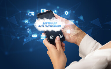 Female hand holding smartphone with SOFTWARE IMPLEMENTATION inscription, cloud technology concept