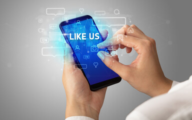 Obraz premium Female hand typing on smartphone with LIKE US inscription, social media concept