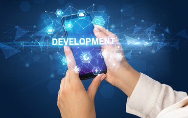 Female hand holding smartphone with DEVELOPMENT inscription, modern technology concept