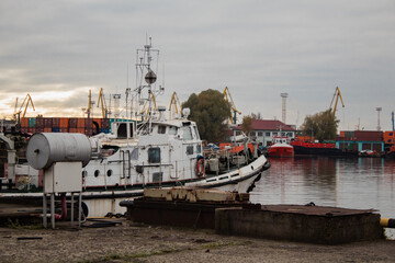 White ship off the coast amid cranes and containers in the port
