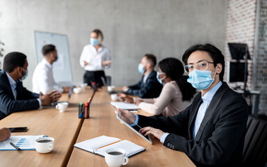 Asian Businessman Entrepreneur In Face Mask Sitting In Modern Office