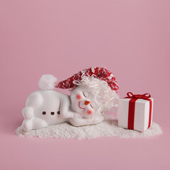 Snowman and gift box on pink background. Winter holiday concept. Minimal christmas background.