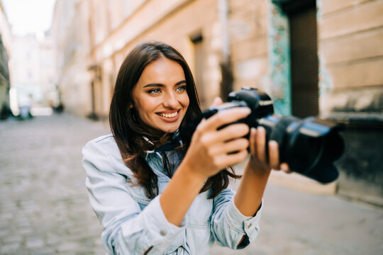 Happy young woman on vacation photographing with camera on the city street