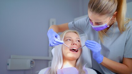 Naklejka premium Dentist Examining Teeth With Medical Instruments Portrait Of Woman Checking His Teeth Professional Dentist Working With Gloves With Patients Teeth With An Open Mouth. Medical Stomatology Concept