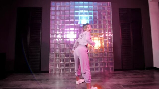 Stylish young woman dancing hip hop, freestyle or swag in the studio. Gimbal shot.