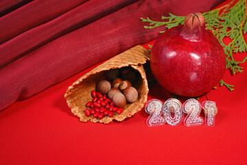 still life from 2021, red pomegranate and a waffle cone with nuts on a red background