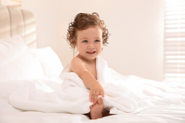 Obraz na płótnie Canvas Cute little baby with soft towel on bed after bath