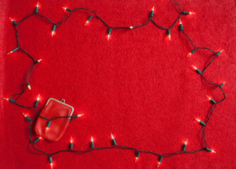 Red wallet on a red background with christmas lights. Christmas expenses concept