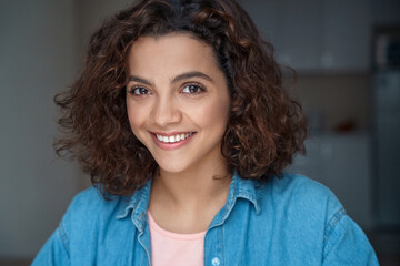 Close-up portrait of beautiful smiling young woman looking at camera at home.