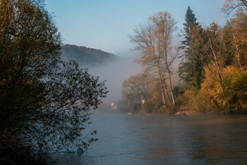 Morning fog over the river with trees on the shore in autumn