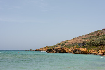 Fototapeta na wymiar Mediterranean Sea shore under blue sky. Ramla Bay beach, Gozo Island, Malta. Selective focus. 