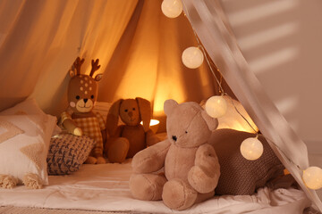 Play tent with toys and pillows indoors, closeup. Modern children's room interior