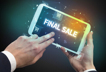 Close-up of a hand holding tablet with FINAL SALE inscription, online shopping concept