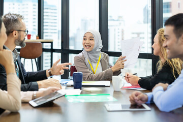 Asian Muslim business woman in hijab headscarf sitting on wheelchair presenting of her work to...