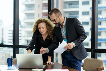 Business man and business woman discussing work with computer laptop, paper chart. Group of businesspeople brainstorming ides in the modern office. businesspeople and office concept