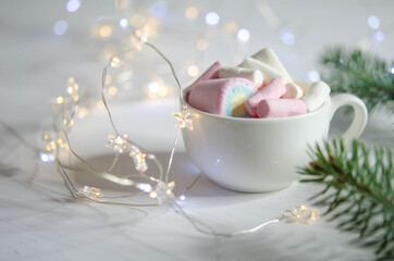 A cup with white-pink marshmallows and fir branches.