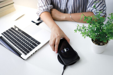 Charging mobile phone battery with wireless charging device in the table. Smartphone charging on a...