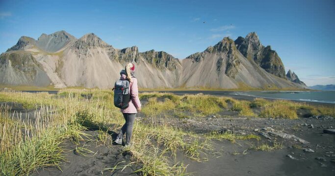 Morning scene of female traveler exploring Stokksnes cape with Vestrahorn (Batman Mountain) on background. Sunny summer day in Iceland