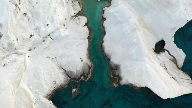 Cinematic aerial drone footage of white rocks and turquoise water on Sarakiniko Beach, Milos Island, Greece