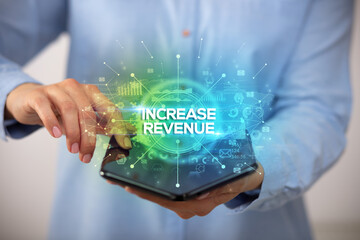 Businessman holding a foldable smartphone with INCREASE REVENUE inscription, new business concept