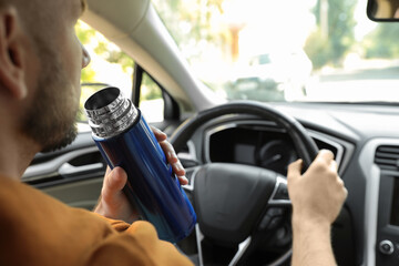 Man with thermos driving car, closeup view