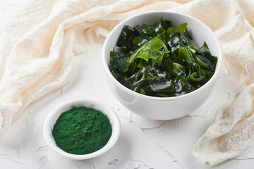 laminaria (Kelp) seaweed and spirulina powder in white bowl background