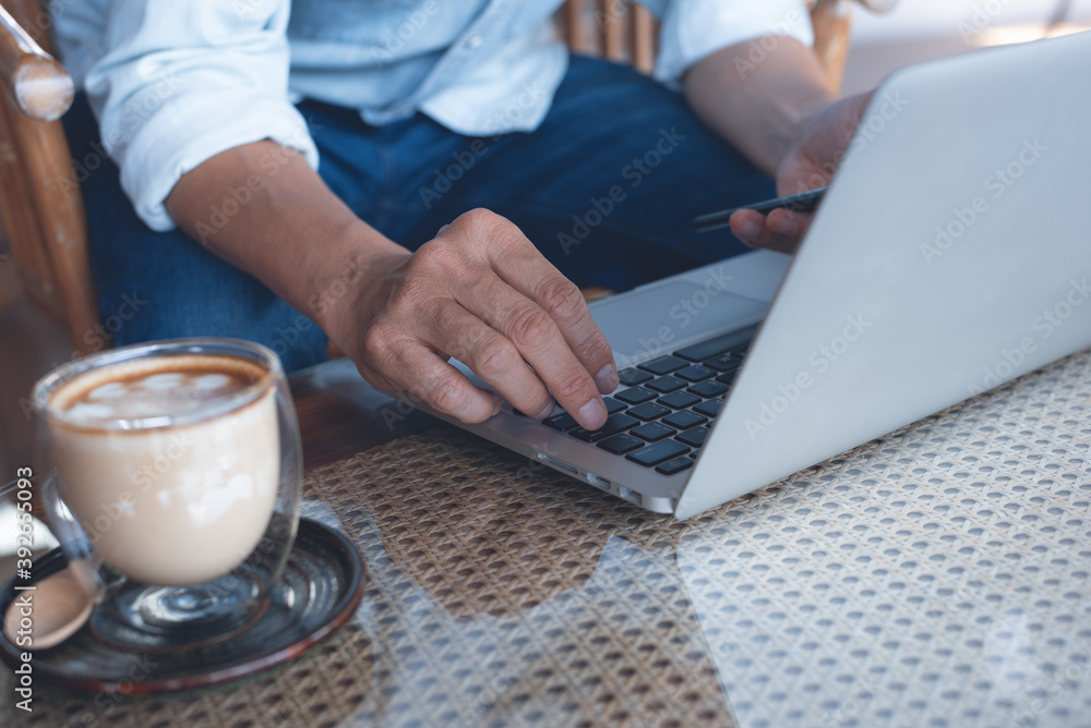 Poster casual business man working on laptop computer and using mobile phone on table in coffee shop