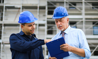 Two architect developers reviewing building plans at construction site