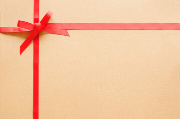 Narrow red ribbon with bow on cardboard gift box. Top view, copy space
