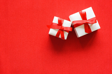 White gift boxes with red ribbon on red background. Xmas and New Year greeting card, winter...