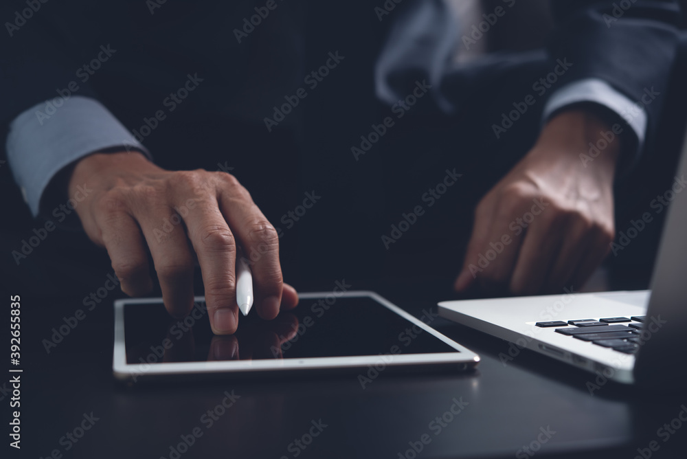 Wall mural Businessman using on digital tablet screen while working on laptop computer in office