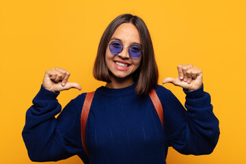 hispanic woman feeling proud, arrogant and confident, looking satisfied and successful, pointing to...