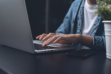 Casual woman hand typing on laptop computer overtime working at night at home office