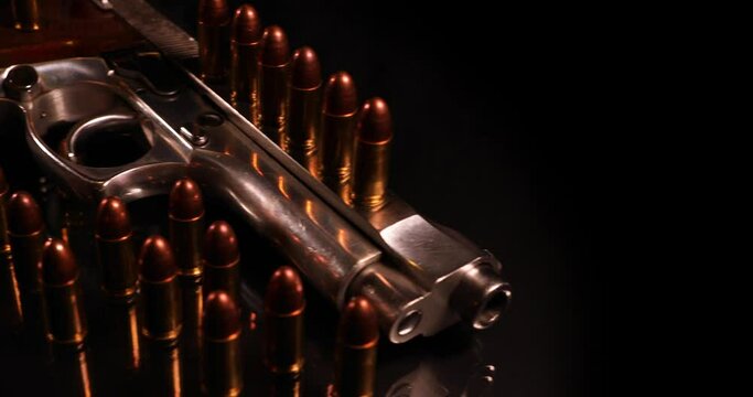 The camera moves along the pistol with cartridges isolated on black background