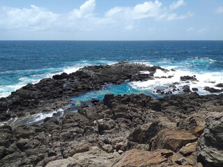 Fototapeta na wymiar Rocky Caribbean coastline with turquoise whitewater under tropical blue sky. Rocks carved by the tropical waters of FWI. Magical environment of wild nature background.