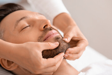 Closeup of man getting healing face massage at spa
