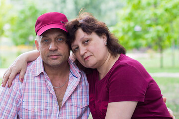 Obraz premium happy middle aged married couple in the park on the bench resting