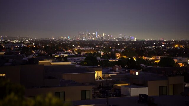 Night skyline of downtown Los Angles illuminating light pollution as air planes slowly fly overhead.