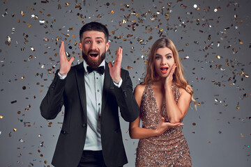 Portrait of excited couple in studio isolated gray shiny background.