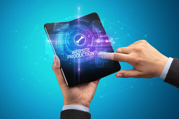 Businessman holding a foldable smartphone with IMPLEMENTATION inscription, new technology concept WEBSITE PRODUCTION