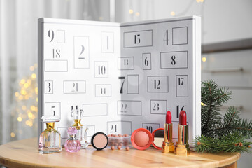 Advent calendar with different cosmetics and perfumes on wooden table against blurred lights....