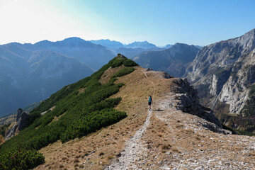 Woman hiking along a mountain ridge in Hochschwab region in Austrian Alps. Endless mountain chains in front. Massive Alps. Autumn vibes in the mountains. Idyllic landscape. Freedom and wilderness