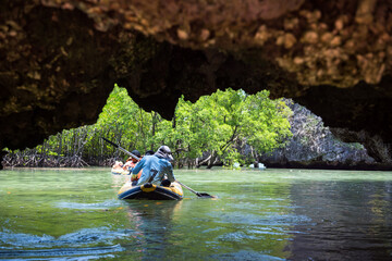 Tourist in canoe at small cave to mangrove forest