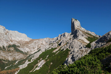 A view on a massive mountain wall in Alps in Hochschwab region, Austria. The slopes are really steep and dangerous to climb. Rocky landscape. Golden grass, autumn vibes. Freedom and wilderness